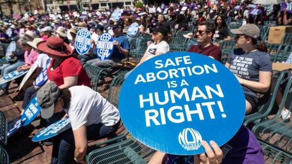 Abortion-rights advocates hold up signs at a rally.